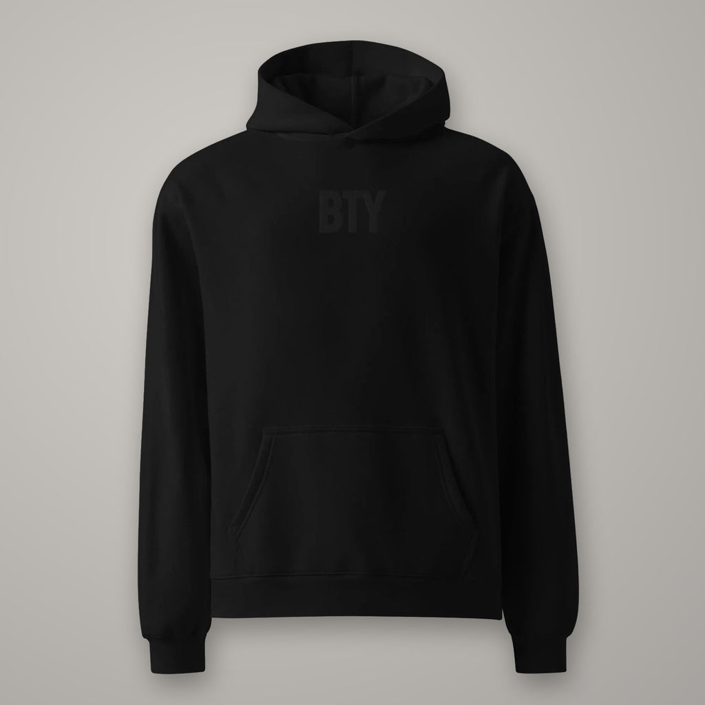 Hoodie Oversize Molleton BTY sur fond studio béton.