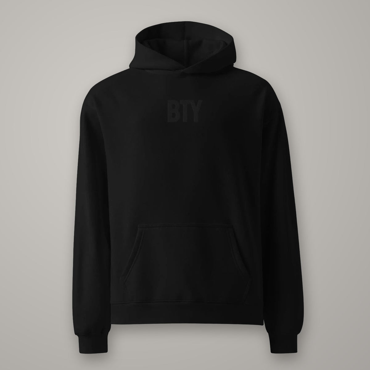 Hoodie Oversize Molleton BTY sur fond studio béton.