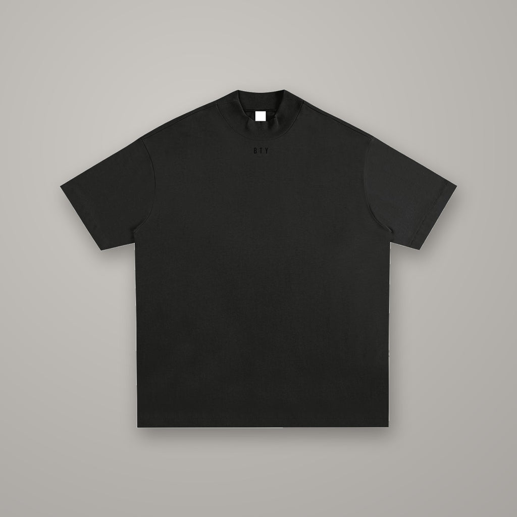 Tee Coton Carrure Tombante BTY, coloris Noir Combat, sur fond studio béton.