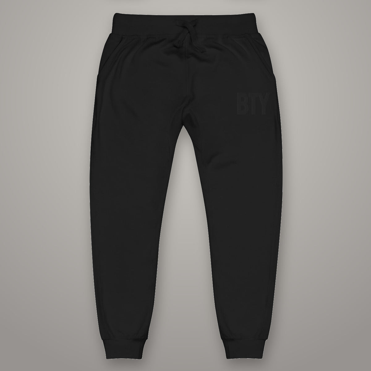 Joggers « Discipline » BTY, Noir Combat, sur fond studio béton.
