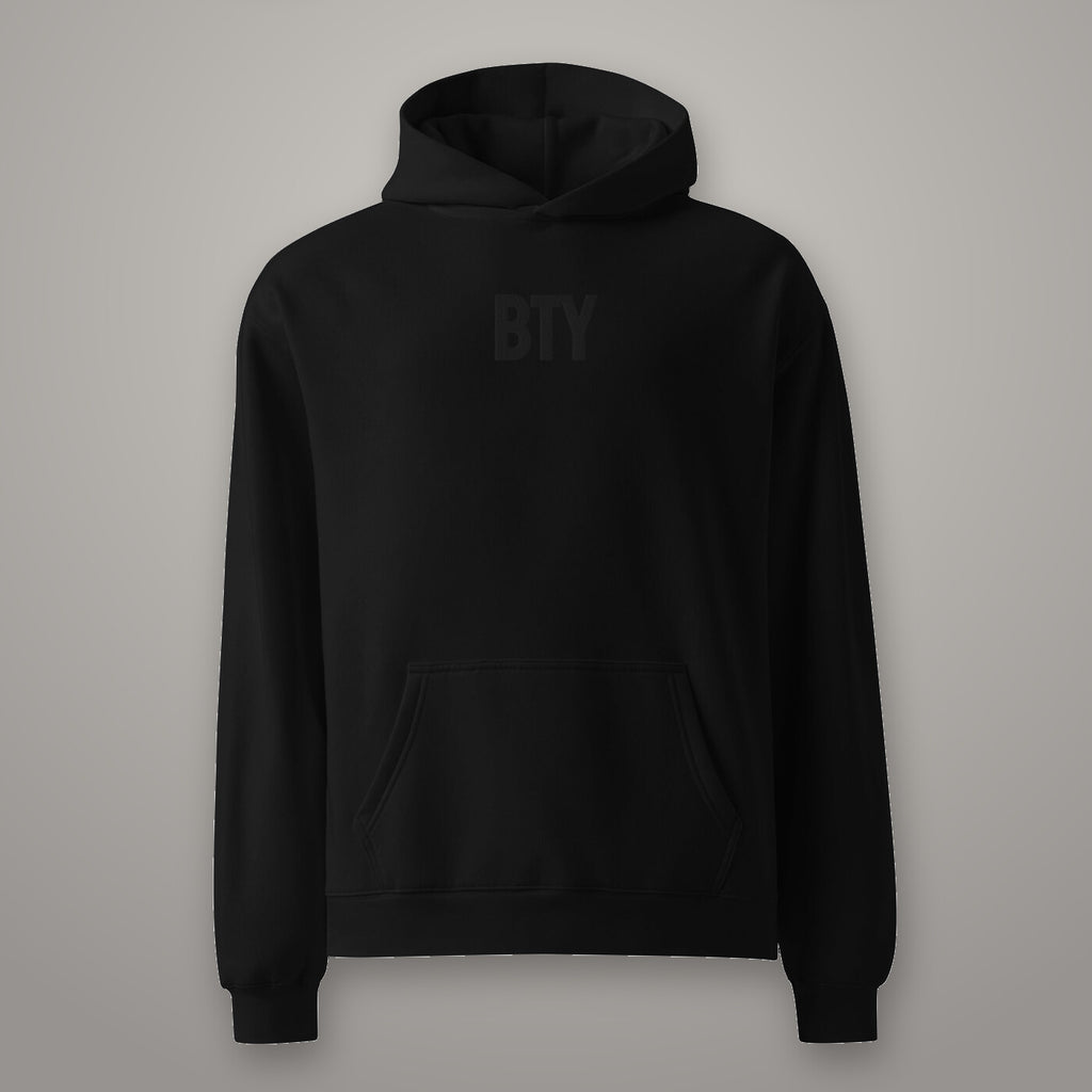 Hoodie « Champion » BTY, Noir Combat, sur fond studio béton.